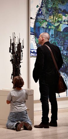 Adult and child visitor looking at a Klippel sculpture and Olsen painting